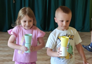 Dzieci w zabawie "Kelner" przenoszą kubeczki.
