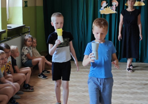 Dzieci w zabawie "Kelner" przenoszą kubeczki.