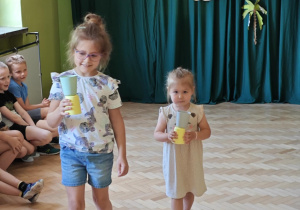 Dzieci w zabawie "Kelner" przenoszą kubeczki.