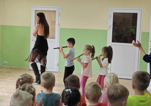 Dzieci grają na fletach razem z artystką.