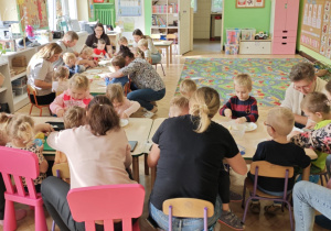 Dzieci przy pomocy rodziców wykonują sałatkę jarzynową.