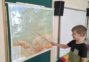 Dziecko wskazuje miasto Łódź na mapie Polski.