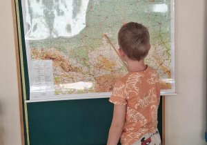 Dziecko wskazuje miasto Łódź na mapie Polski.