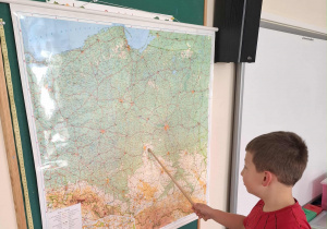Dziecko wskazuje miasto Łódź na mapie Polski.