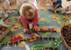 Dzieci układają rytmy ze zgromadzonych darów jesieni.