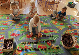 Dzieci układają rytmy ze zgromadzonych darów jesieni.