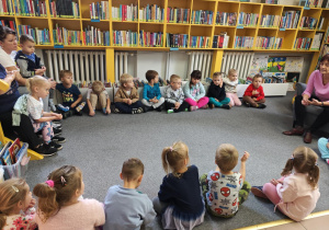 Dzieci słuchają opowiadania o wiewiórce, czytanego przez Panią z Biblioteki.