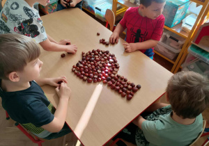 Dzieci układają wzory z kasztanów.