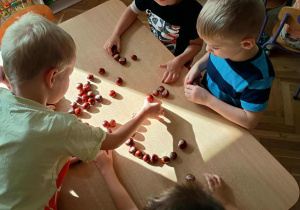 Dzieci układają wzory z kasztanów.