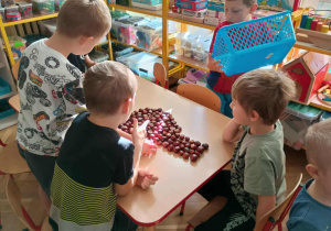 Dzieci układają wzory z kasztanów.