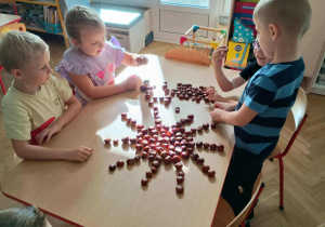 Dzieci układają wzory z kasztanów.