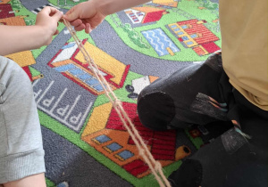 Dzieci doskonalą umiejętność przeliczania i porównywania długości wykorzystując sznurek z supełkiem.