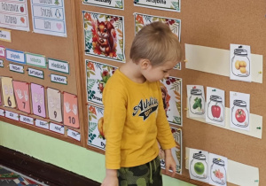 Dziecko wskazuje, półkę, na której stoją dwa słoiki.