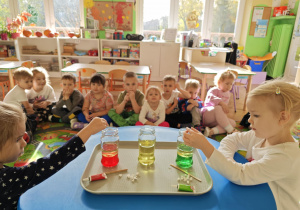 Dzieci obserwują zmiany zachodzące w słoiku po dodaniu musującej tableki.