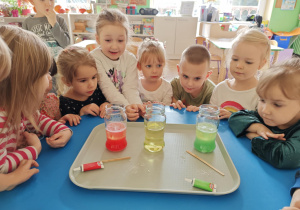 Dzieci obserwują zmiany zachodzące w słoiku po dodaniu musującej tableki.