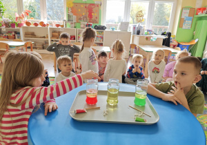 Dzieci obserwują zmiany zachodzące w słoiku po dodaniu musującej tableki.