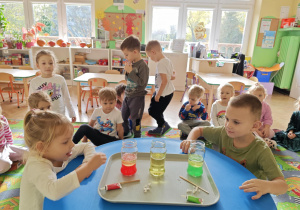 Dzieci obserwują zmiany zachodzące w słoiku po dodaniu musującej tableki.