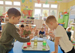 Dzieci obserwują zmiany zachodzące w słoiku po dodaniu musującej tableki.