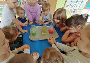 Dzieci obserwują zmiany zachodzące w słoiku po dodaniu musującej tableki.