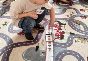 dziecko układa obrazki na dywanie