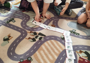 dziecko układa obrazki na dywanie