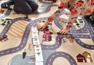 dziecko układa obrazki na dywanie