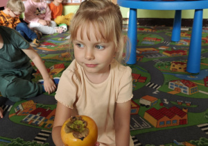 Dziecko rozpoznaje za pomocą dotyku jaki pomarańczowy owoc lub warzywo ukrył się w torebce.