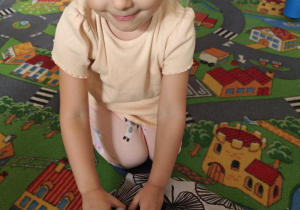 Dziecko rozpoznaje za pomocą dotyku jaki pomarańczowy owoc lub warzywo ukrył się w torebce.