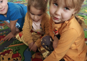 Dziewczynka rozpoznaje za pomocą dotyku pomarańczowy owoc.