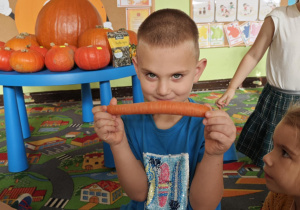 Dziecko rozpoznaje za pomocą dotyku jaki pomarańczowy owoc lub warzywo ukrył się w torebce.