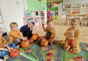 Dzieci siedzą przy swoich ozdobionych dyniach.