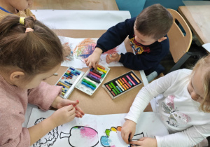 Dzieci ozdabiają szablony drzew jesiennymi barwami.