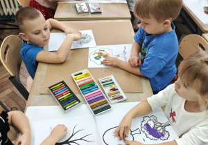 Dzieci ozdabiają szablony drzew jesiennymi barwami.