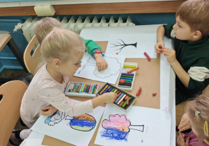 Dzieci ozdabiają szablony drzew jesiennymi barwami.