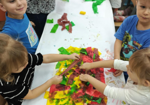 Dzieci malują bibułą, tworząc tło do dalszego etapu pracy.