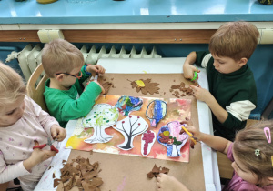 Dzieci tną jesienne liscie na małe kawałki.