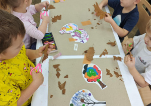 Dzieci tną jesienne liscie na małe kawałki.