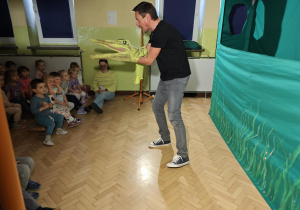 Aktor zbliża się zpacynką krokodyla do widowni.