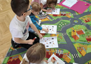 Dzieci wykonują zadania z karty pracy.