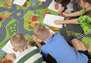 Dzieci wykonują zadania z karty pracy.