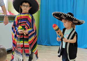 Dzieci ubrane w tradycyjne meksykańskie stroje grają na instrumentach.