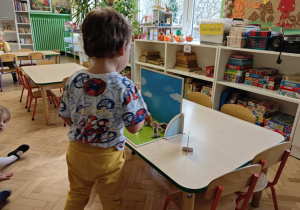 Dzieci słuchają bajki o trzech świnkach, kolejno podchodzą i dokładają rekwizyty na scenę.