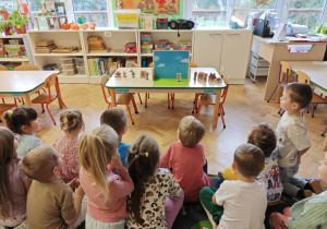 Dzieci słuchają bajki o trzech świnkach.