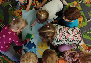 Dzieci podzielone na dwie grupy układają figury geomeryczne na poszczególnych polach wg określonych cech.