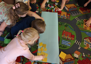 Dzieci podzielone na dwie grupy układają figury geomeryczne na poszczególnych polach wg określonych cech.