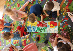 Dzieci podzielone na dwie grupy układają figury geomeryczne na poszczególnych polach wg określonych cech.