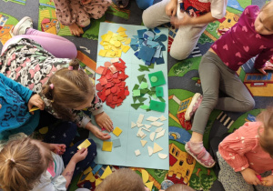 Dzieci podzielone na dwie grupy układają figury geomeryczne na poszczególnych polach wg określonych cech.