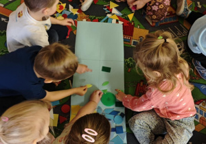 Dzieci podzielone na dwie grupy układają figury geomeryczne na poszczególnych polach wg określonych cech.