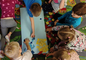 Dzieci podzielone na dwie grupy układają figury geomeryczne na poszczególnych polach wg określonych cech.