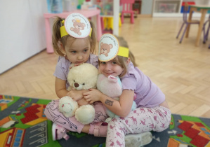 Dzieci przytulają się do misia.